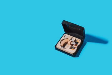 Hearing aid in a box case on a blue background under hard light.