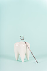 Healthy white tooth model and dentist mirror on blue background. Copy space. Teeth care, whitening,...