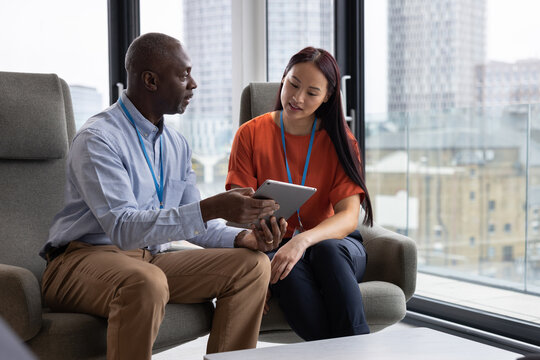 Young businesswoman being mentored by senior businessman in a modern office with view of city