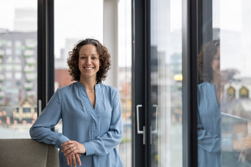 Portrait of businesswoman in corporate office with view of city skyline