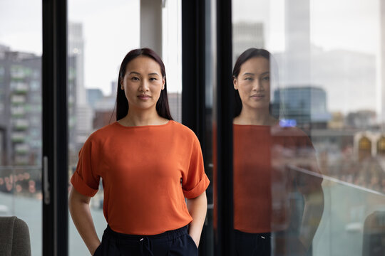Portrait of young asian businesswoman in corporate office with view of city skyline