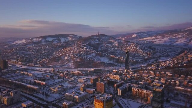 Aerial cinematic drone Avaz Twist Tower snowy roads winter Olympic downtown snowy frozen Sarajevo City town center Bosnia and Herzegovina landscape afternoon sunset golden purple circle right movement