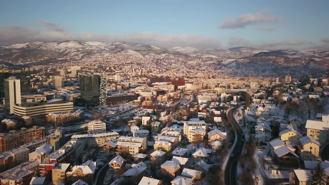 Aerial cinematic drone cars driving snowy roads winter Olympic downtown snowy frozen Sarajevo City town center Bosnia and Herzegovina frozen landscape afternoon sunset golden pan up forward movement