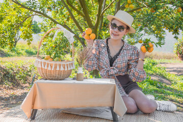 Happy Cute thai girl holding oranges with orange basket in orange farm in Chiang Mai, Thailand.