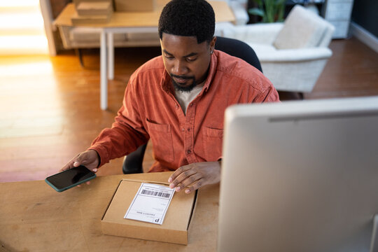 African American male entrepreneur using smartphone to view order details from e-commerce site