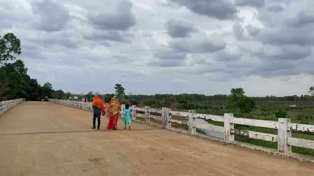 Newly wedded couple walking with a child in a bridge in Jharkhand with dark cloudy weather.