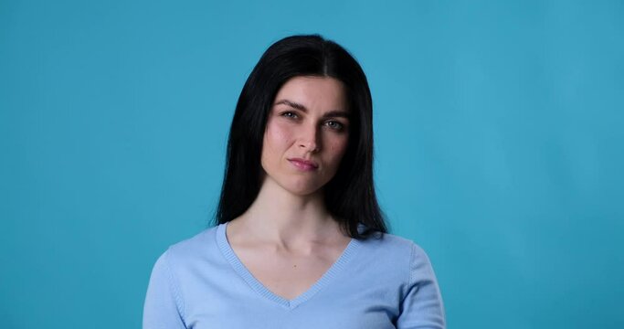 Caucasian woman wearing casual clothing and standing on a blue background shows a negative gesture with her hand thumb down