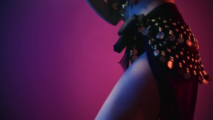 Exotic female belly dancer skirt rhinestone dancing shaking hip waist at dark light studio closeup