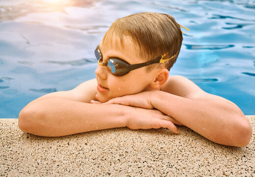 Smiling boy portrait in swimming goggles, Child swim in the pool, sunbathes, swimming in hot summer day. Relax, Travel, Holidays, Freedom concept.
