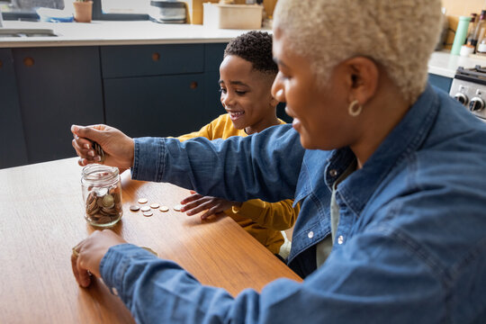 Mother and son saving coins in an old jar