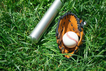 Naklejka premium Baseball bat and baseball on the green grass background.