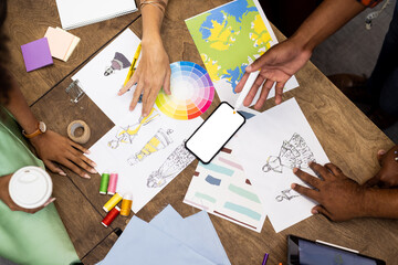 Diverse fashion designers using smartphone with copy space in office, unaltered