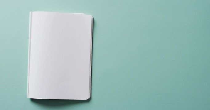 Close up of open blank book with copy space on green background in slow motion
