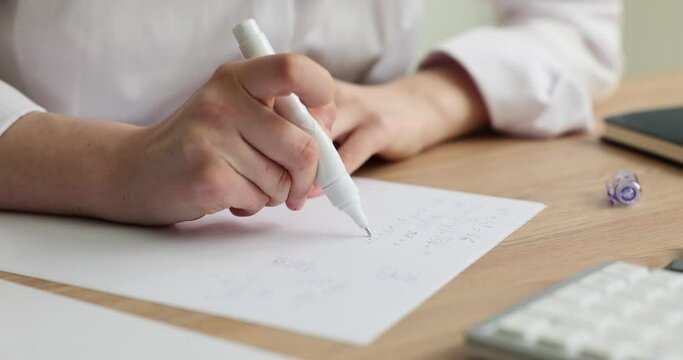 Woman removes wrong text with corrector pen sitting at wooden table slow motion. Employee changes written words. Quick drying liquid eraser