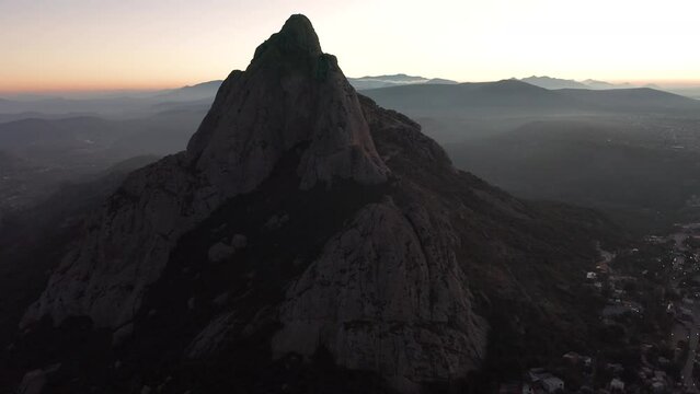 Rotating drone view of Pena de Bernal mountain with canyon rocky hills at sunset in Mexico
