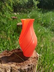 3D printed vase. 3D printed vase with green grass and bushes in the background