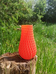 3D printed vase. 3D printed vase with green grass and bushes in the background