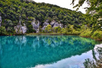 Obraz premium Scenic view of reflective Plitvice lakes surrounded by mountain forests in Croatia
