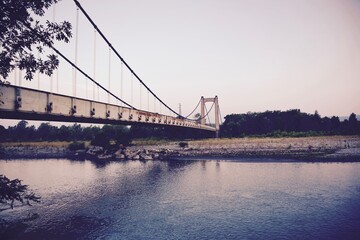 Bridge over the river against the background of green trees on the shore.