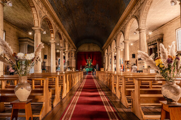 People at the alter of a beautiful church with a red carpet and pews in Chonchi, Chiloe, Chile - obrazy, fototapety, plakaty
