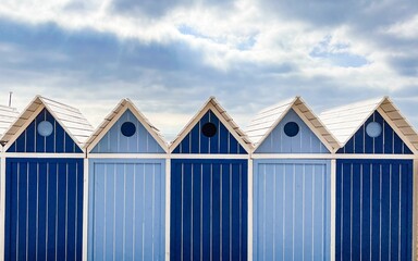 Facade of a row of blue cabins by the sea - obrazy, fototapety, plakaty