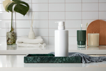 Front view of cosmetic bottle unlabeled placed on marble tray with gray towel, in the background is...