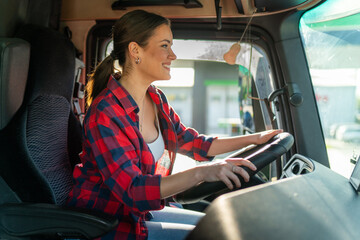 beautiful young woman professional truck driver sitting and driving big truck cross country.