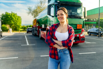 Junior female truck driver standing in front of her truck after she successfully completed her...
