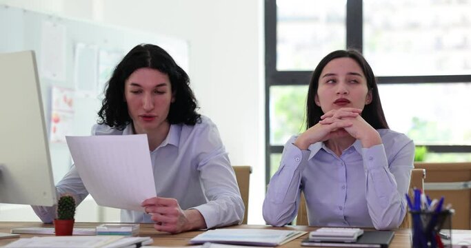Couple of office workers discusses papers and considers solutions. Annoyed male manager reads report aloud and female coworker listens thoughtfully