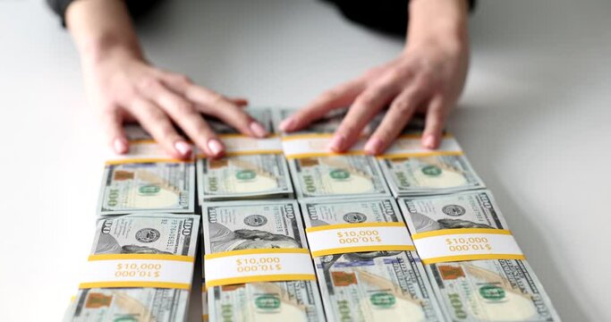 Woman moves away stacks of dollar banknotes on white table making deal with partner. Businesswoman offers money for services. Female refuses to take bribe