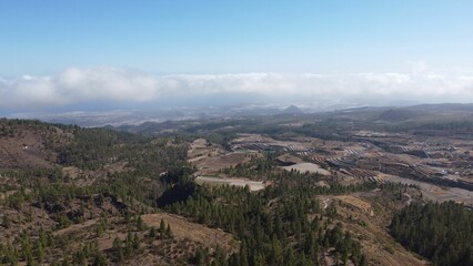 Naklejka premium High-altitude farmland in Tenerife from above clouds, looking down towards the coast, aerial