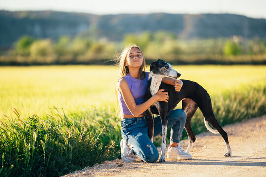 Portrait of a beautiful young blond woman with her greyhound dog.
