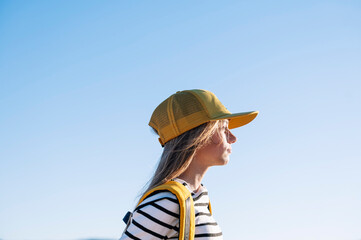 Outdoor portrait of a beautiful young blonde woman in a yellow cap and a bracket on her teeth.