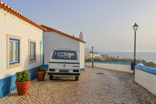 Restored white old Volkswagen van parked on a cobblestone road near the road