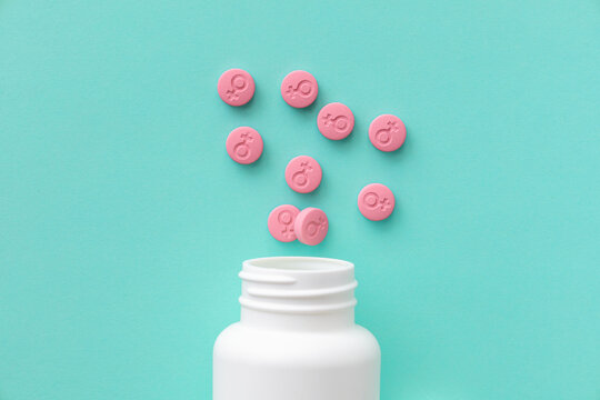 Female gender symbol on pink pills. Pills for women. Contraceptives or menstrual days. A jar with pills on a green background. Top view.