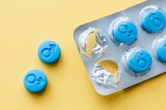 Pills for men. Male gender symbol on blue pills. Yellow background
