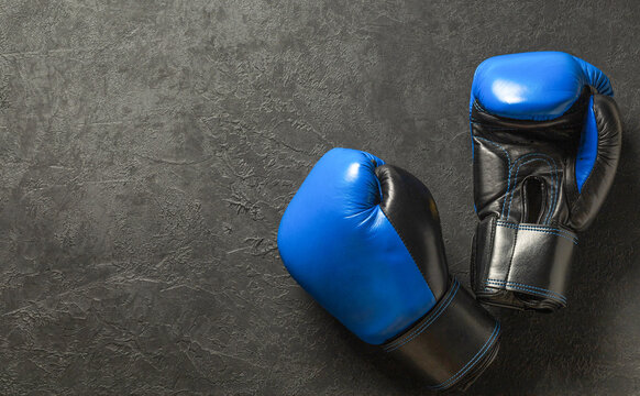 Blue and black boxing gloves on a black background. Free space for text