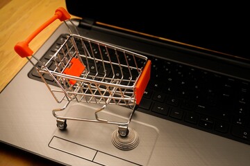 Online shopping concept with miniature cart on stack of coins on a notebook