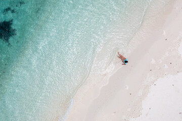 Fototapeta na wymiar Frau sitzt am weißen Strand der Malediven