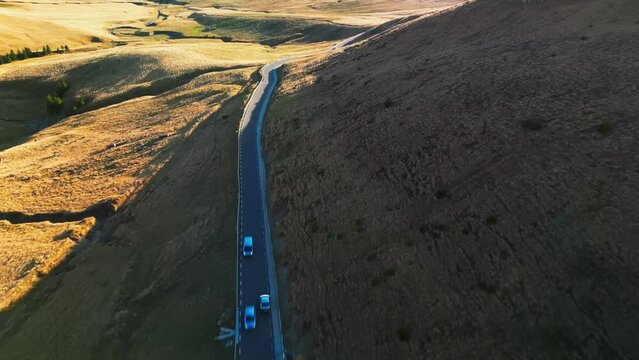 Cars driving through Piatra Arsa chalet road in Bucegi mountains, Romania. Aerial