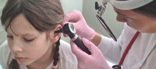 Pediatrician ENT examines small patient with otoscope - obrazy, fototapety, plakaty