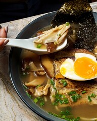 Vertical close-up of shiitake mushrooms of a miso pork ramen noodle soup