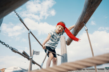 A little boy dressed as a pirate plays on a wooden playground