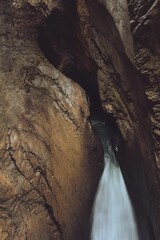 Vertical long exposure shot of a waterfall flowing from a cave in a mountain