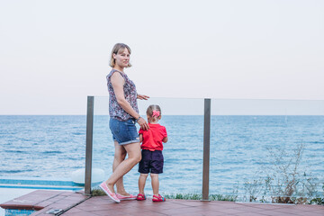 Fototapeta na wymiar Mother and daughter stand by the seashore and look at the horizon