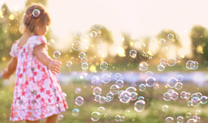 abstract blurred natural background with baby girl and many fly soap bubbles outdoor. dreaming...