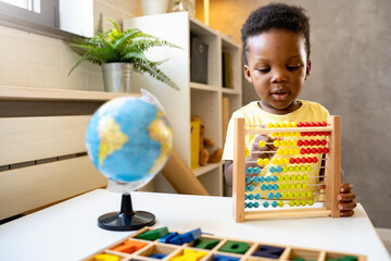 A cute little African child plays with a colorful wooden abacus toy. Educative toys.