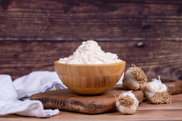 Fototapeta na wymiar Garlic powder on wooden background. Dried ground garlic powder spices in wooden bowl