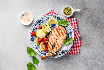 Grilled salmon steaks with spices, lemons and grilled zucchini on plate. Top view of fried fish with copy space. Keto recipe.