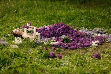 portrait of a girl in a lilac dress lying on the grass, taken at sunset